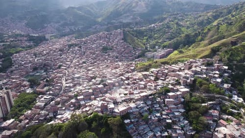 Sunlit Comuna 13 favela sprawling up Medellin hills, Colombia - aerial
