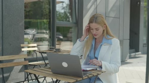 Woman Working with Laptop at Outdoor Cafe Table