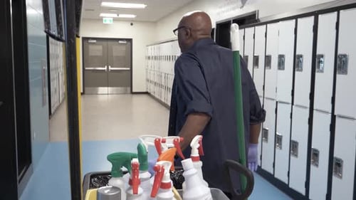 Plan filmé au ralenti d'un concierge d'école tirant un chariot dans le corridor du Canada