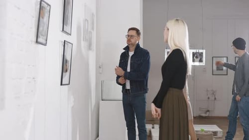 Men and Women in an Art Gallery Inspect the Abstract Works of Contemporary Artists