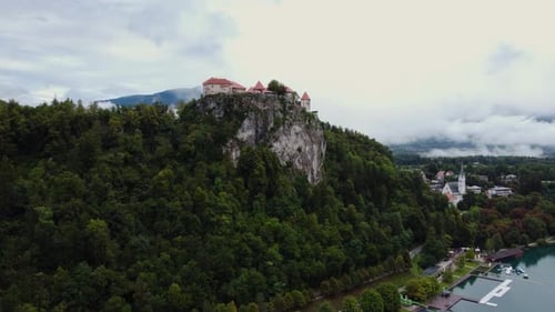 AERIAL Approaching Shot of Bled Castle in Lake Bled, Slovenia on a Cloudy Day