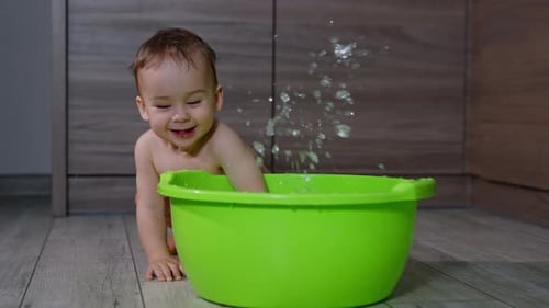 Happy Baby Splashing Water in Green Tub