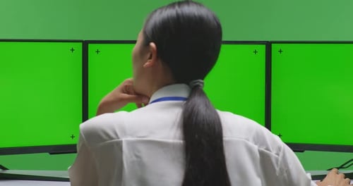 Back View Asian Woman Thinking While Working With Mock Up Multiple Computer Monitor In Green Screen