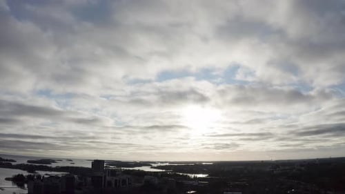 Tilt up arial view of coastal city and sunset behind the clouds.