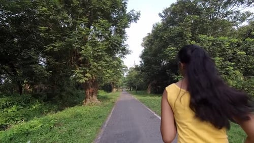 Teenager Athlete girl jogging at morning sunrise on road with trees