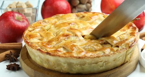 Cutting fresh apple pie on a wooden board
