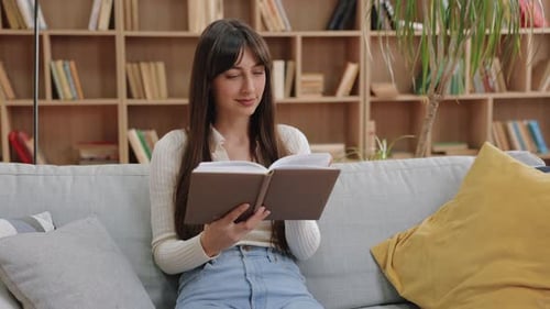 Woman Reading a Book on Sofa at Home