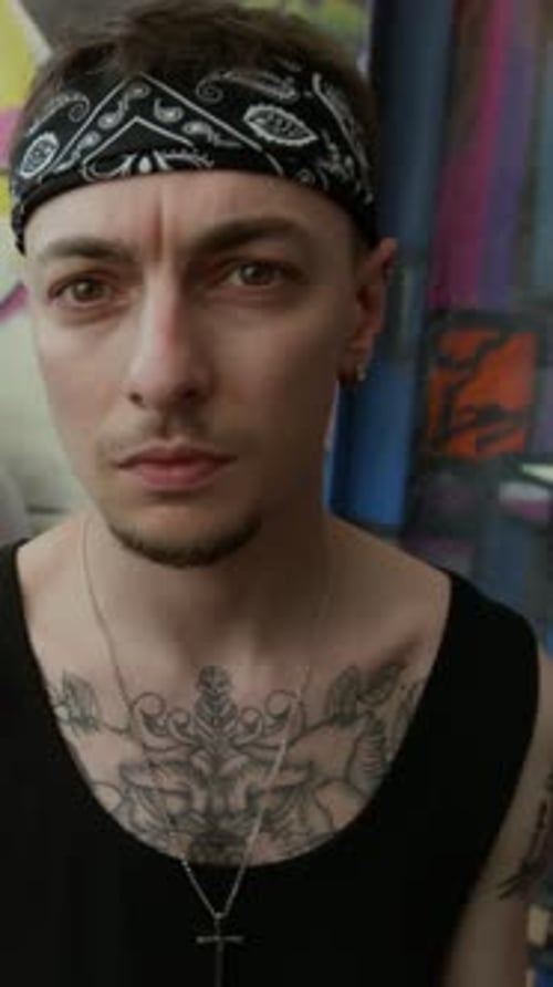 Porträt eines selbstbewussten tätowierten Mannes mit Bandana vor einer Graffiti-Wand