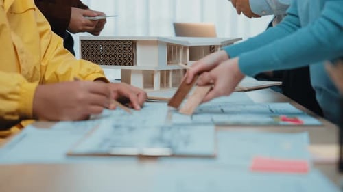 Architectural Team Collaborating on Building Model and Blueprints