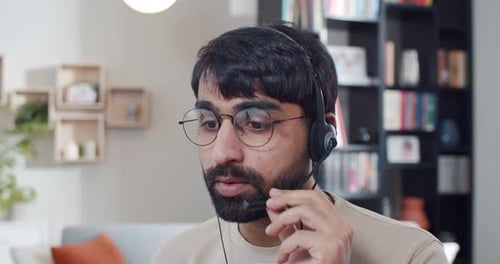 Close Up of Indian Young Man in Headset Talking and Videochatting at Home Call Center Worker at Home