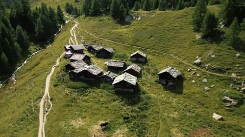 Orbit drone shot of traditional Swiss chalet near Arolla's Blue Lake during the day in Val d'Herens