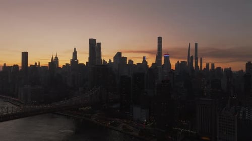 Sunset Casts Orange and Blue Glow Over New York City Skyline Highlighting the Queensboro Bridge and