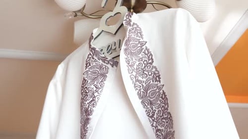 04 An der Lampe hängt eine weiße bestickte Herrenjacke.