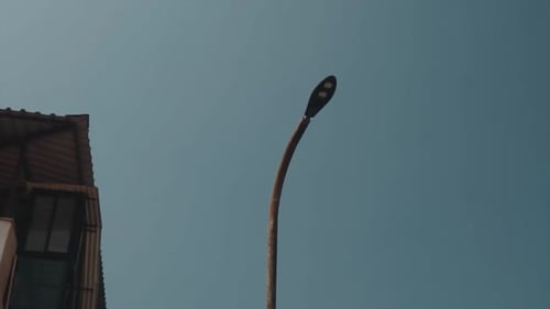 Panning shot of a turned off steel street light pole at twilight with clear sky