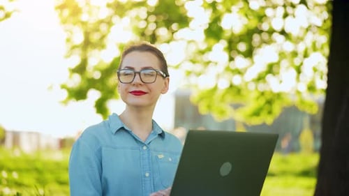 Busy Attractive Woman Working at the Laptop As Sitting on Grass in City Park