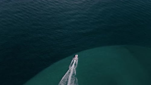 Aerial Wide Shot of a White Boat Sailing to the Blue Sea Moving at High Speed