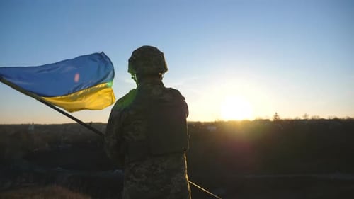 Soldier Holds Flag on Hill at Sunrise