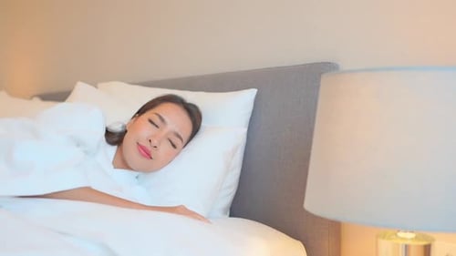 Beautiful young Asian woman sleeping well in comfortable bed of hotel bedroom