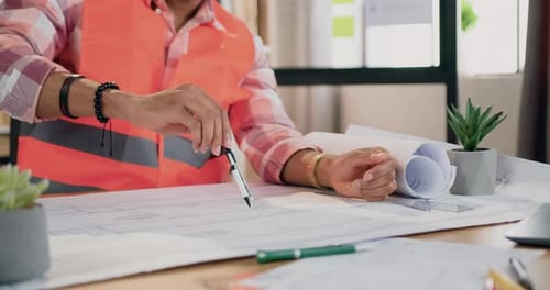 Unknown professional man engineer in vest drawing circle with compass on large format paper plan