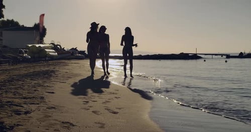 Friends Joyfully Walking on the Beach at Sunset Creating Lasting Memories Together