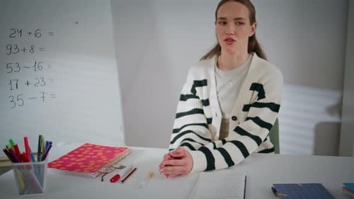 Teacher Explains Math Problems at Desk