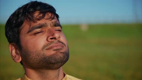 Young Indian Man Enjoying Fresh Air in Green Meadow