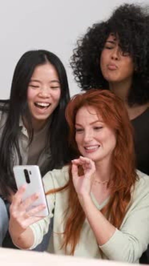 Fröhliche, vielfältige Freunde, die ihr Smartphone zu Hause benutzen