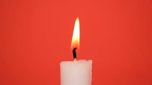 Burning Candle Flame Against Red Background