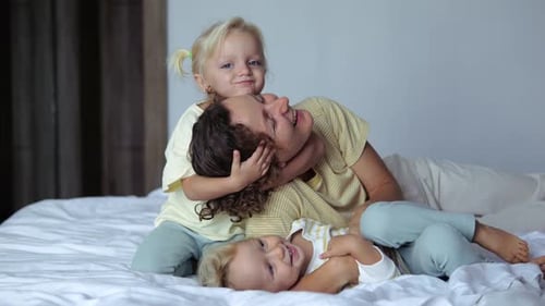 Playful Parent with Two Children Bonding on Bed