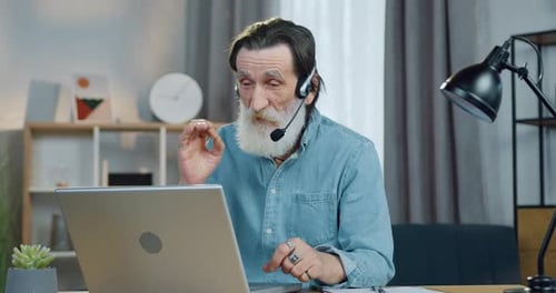 Senior Man Working on Laptop with Headset