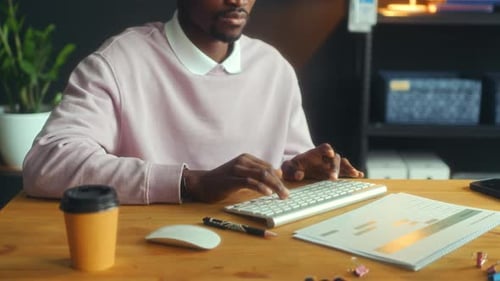 Close-Up of Black Man Typing on Computer Keyboard at Office Desk
