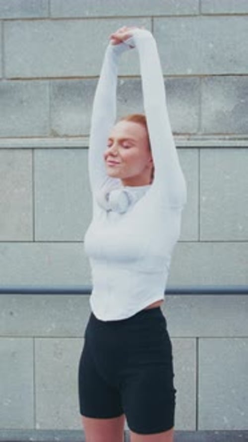 Woman Stretching Arms Overhead in Urban Setting