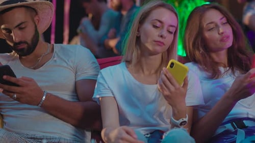 Young Adults on Phones at Nighttime Urban Event