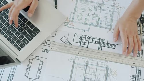 Architekt arbeitet an CAD und überprüft Baupläne auf Laptop und Schreibtisch