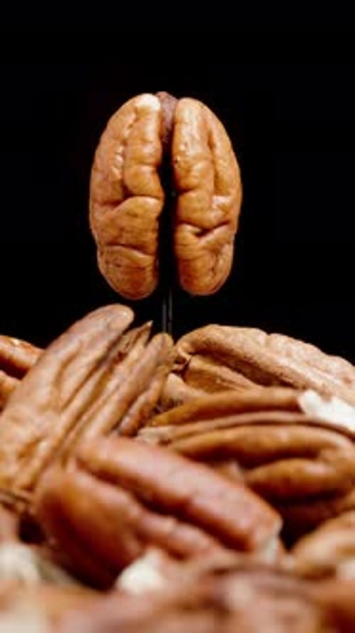Vertical video. A Pile of Peeled Pecans, on Top of Which Rotates a Whole Nut in Close-Up.
