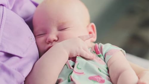 Cute Newborn Baby Girl Sleeping in Her Mothers Arms Closeup