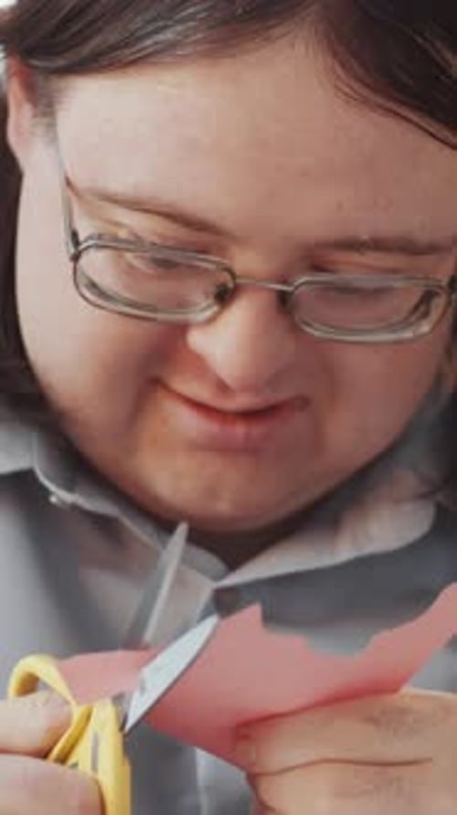 Person Cutting Pink Paper with Scissors, Close Up