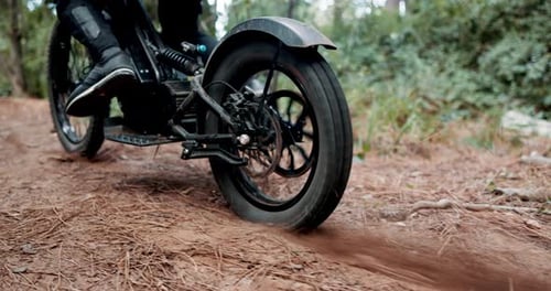 Person, dirt bike and feet on forest trail with tyre spin, speed and start with dust for adventure