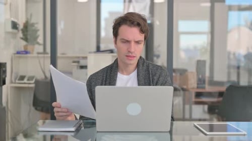 Focused Young Adult Reviewing Documents in Modern Office