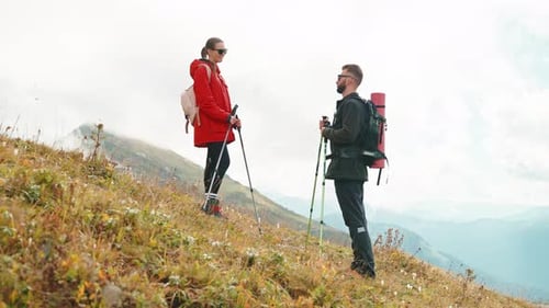 Two Hikers in Mountain Man and Woman with Equipment for Touristic Trip in Nature Standing on Slope