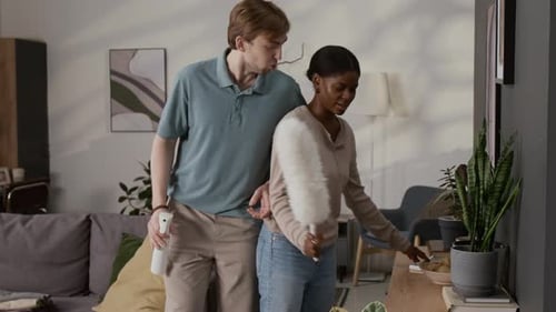 Multiethnic Young Couple Doing Housework, Dancing Energetically and Singing