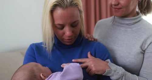Two Women Holding a Baby in a Home