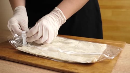 Chef Opens Package of Pita Bread on Board