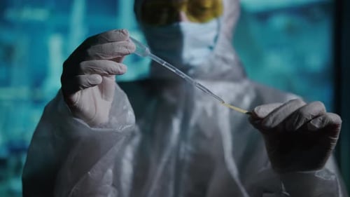 Virologist in a Protective Suit is Testing the Substance with a Litmus Test Search for a Vaccine and