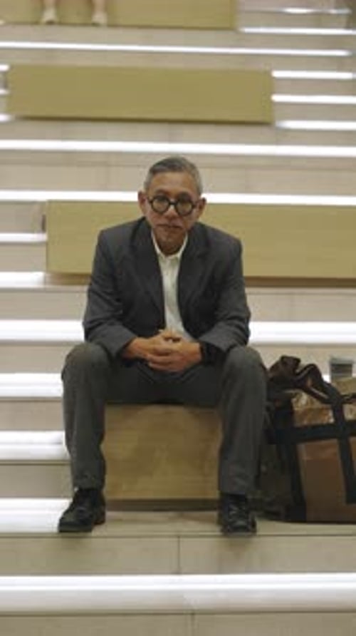 Man in Suit Sitting on Stairs with Bag