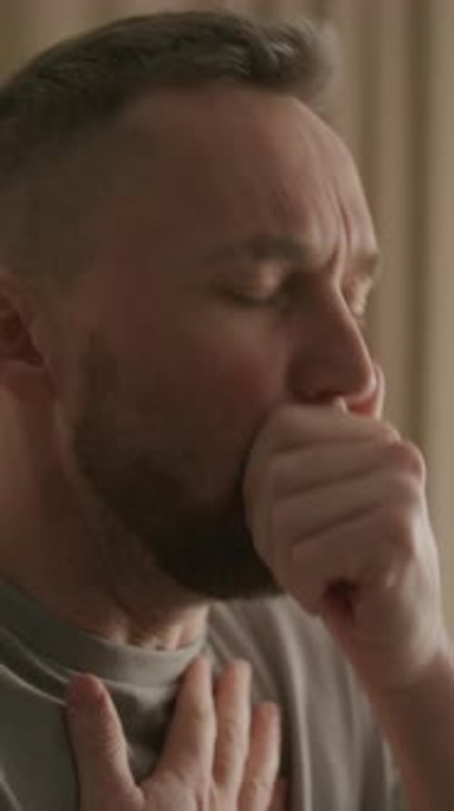 Man Caughing With Fist to Mouth Indoors