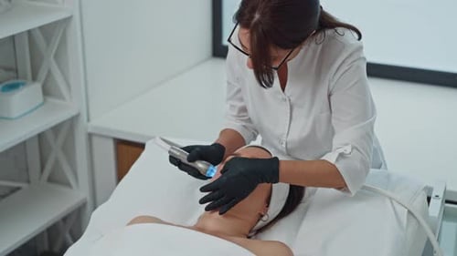 A Cosmetologist Performs a Beauty Procedure with a Device in the Doctor's Office