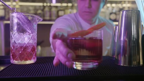 Bartender n the Bar Making Drink at Bar with Orange Zest