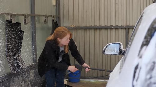 A Woman Applying White Active Foam to a Dirty Car at a Selfservice Car Wash
