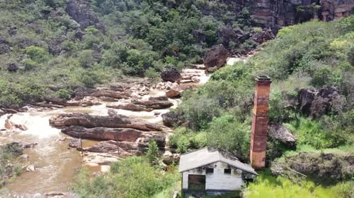 an old abandoned building beside a rocky river in barren hills. 4K videos. long summer days. from to